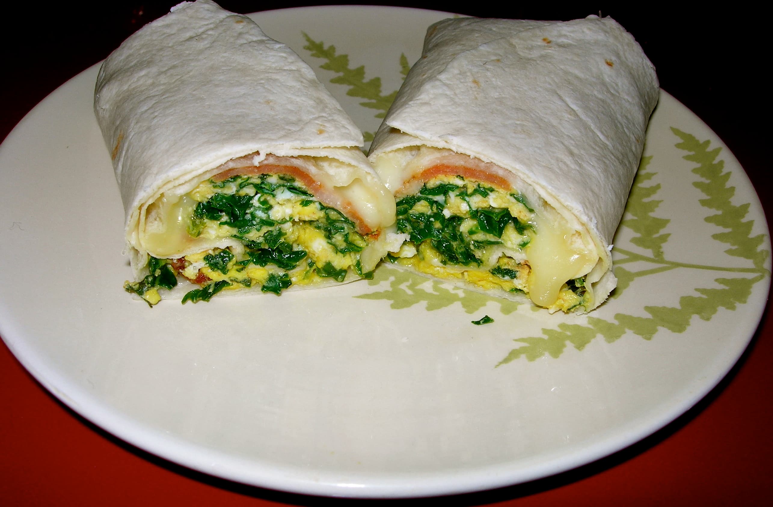 Breakfast burrito — a american breakfast dish from United States — featuring flour tortilla wrap, Southwestern origin, scrambled eggs and potatoes
