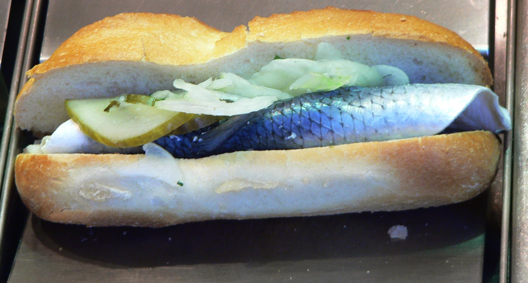 Fischbrötchen — a german drink dish from Germany — featuring brined & vinegared, layered condiments, handheld street food