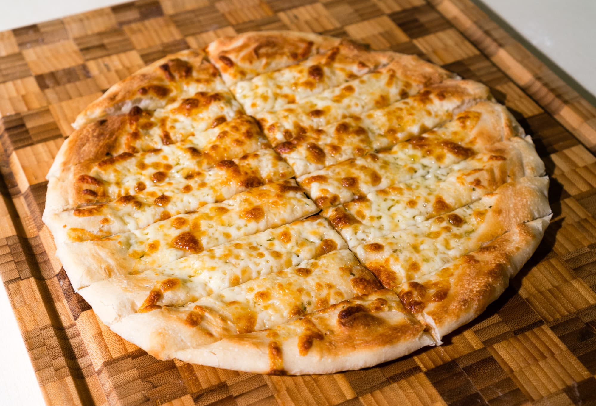 Garlic fingers — a canadian main course dish from Canada — featuring garlic butter base, cheese-topped strips, dipped in donair sauce