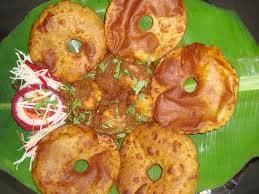 Kombdi vade — a indian main course dish from India — featuring bone-in curry, fried dumplings, coconut gravy