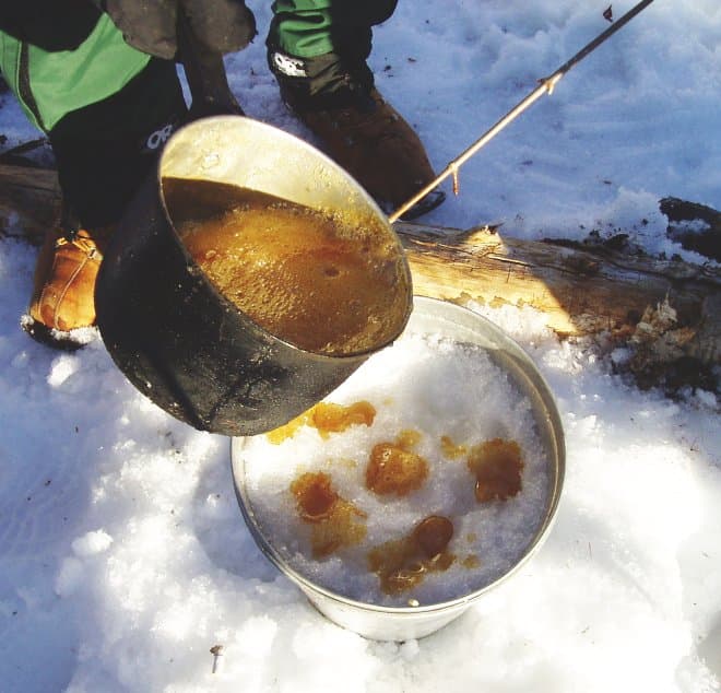 Maple taffy — a canadian main course dish from Canada — featuring boiled maple sap, snow-set candy, wooden-stick tradition