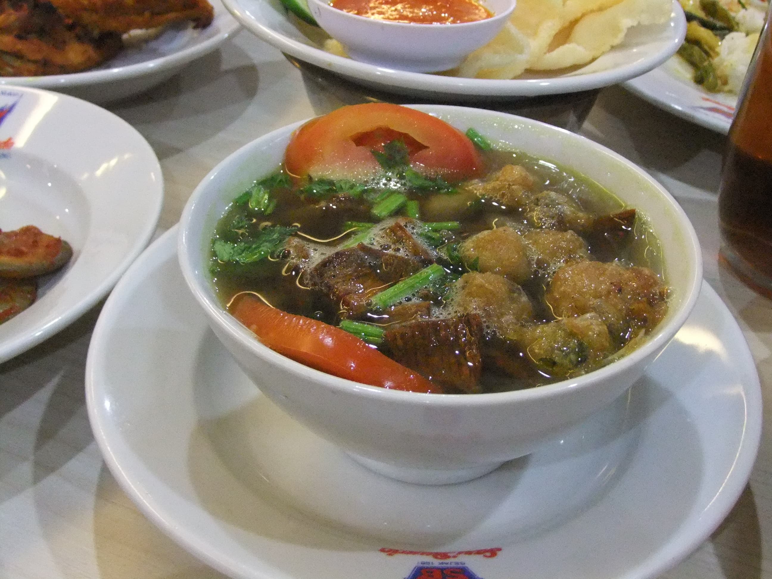 Soto padang — a indonesian breakfast dish from Indonesia — featuring clear broth, beef two ways, fried potato patties