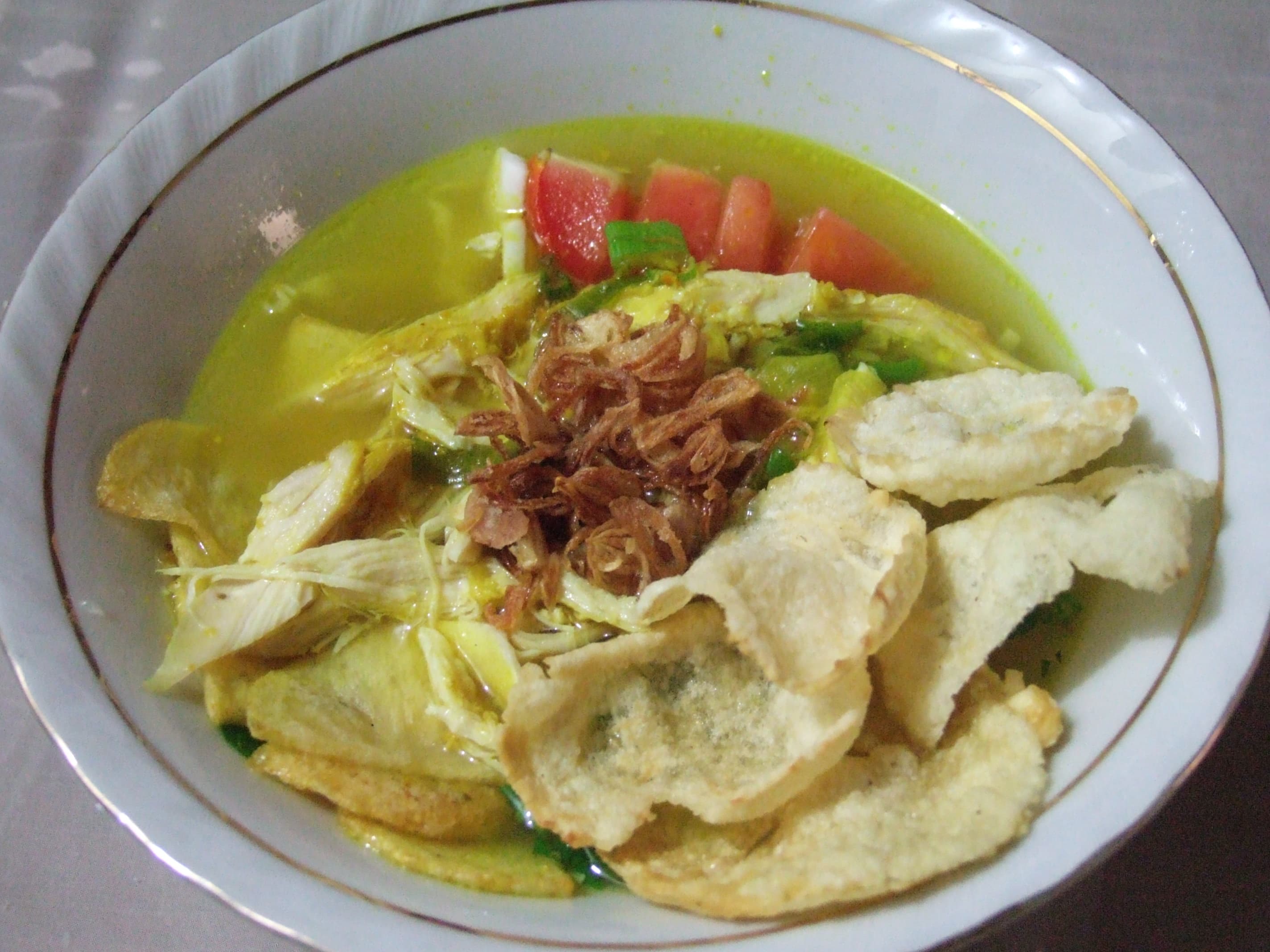 Soto ayam — a indonesian main course dish from Indonesia — featuring turmeric-broth, coconut-milk-finish, layered-toppings