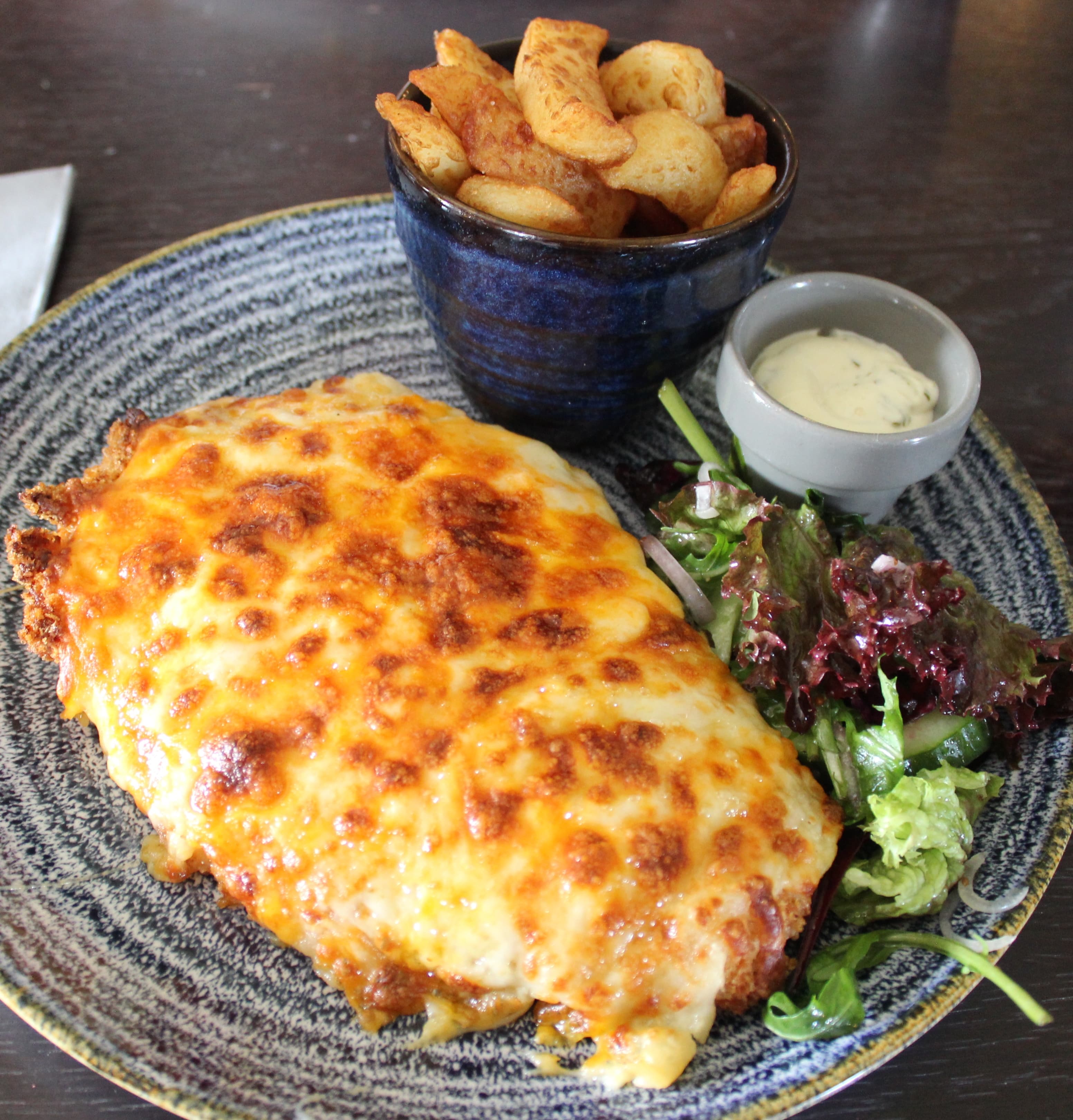 Parmo — a british main course dish from United Kingdom — featuring breaded cutlet, béchamel-topped, cheese-laden