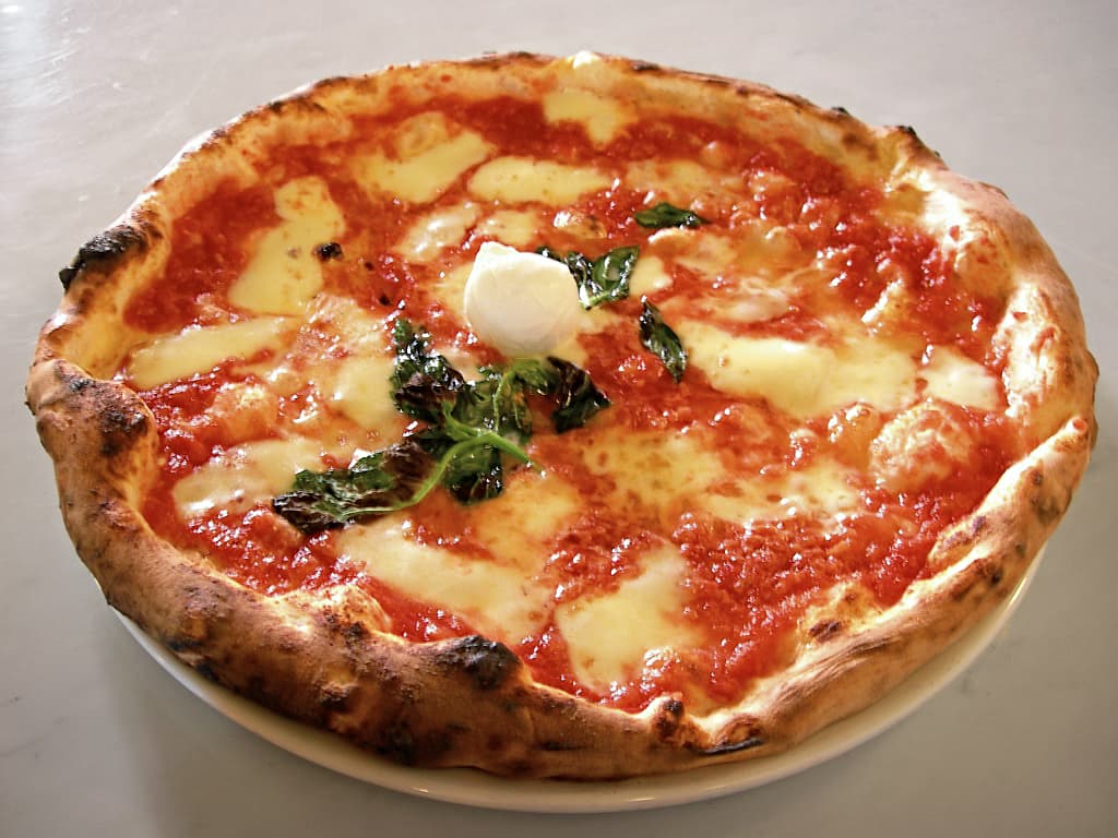 Pizza — a italian street food dish from Italy — featuring leavened wheat dough, high-heat baked, wood-fired tradition