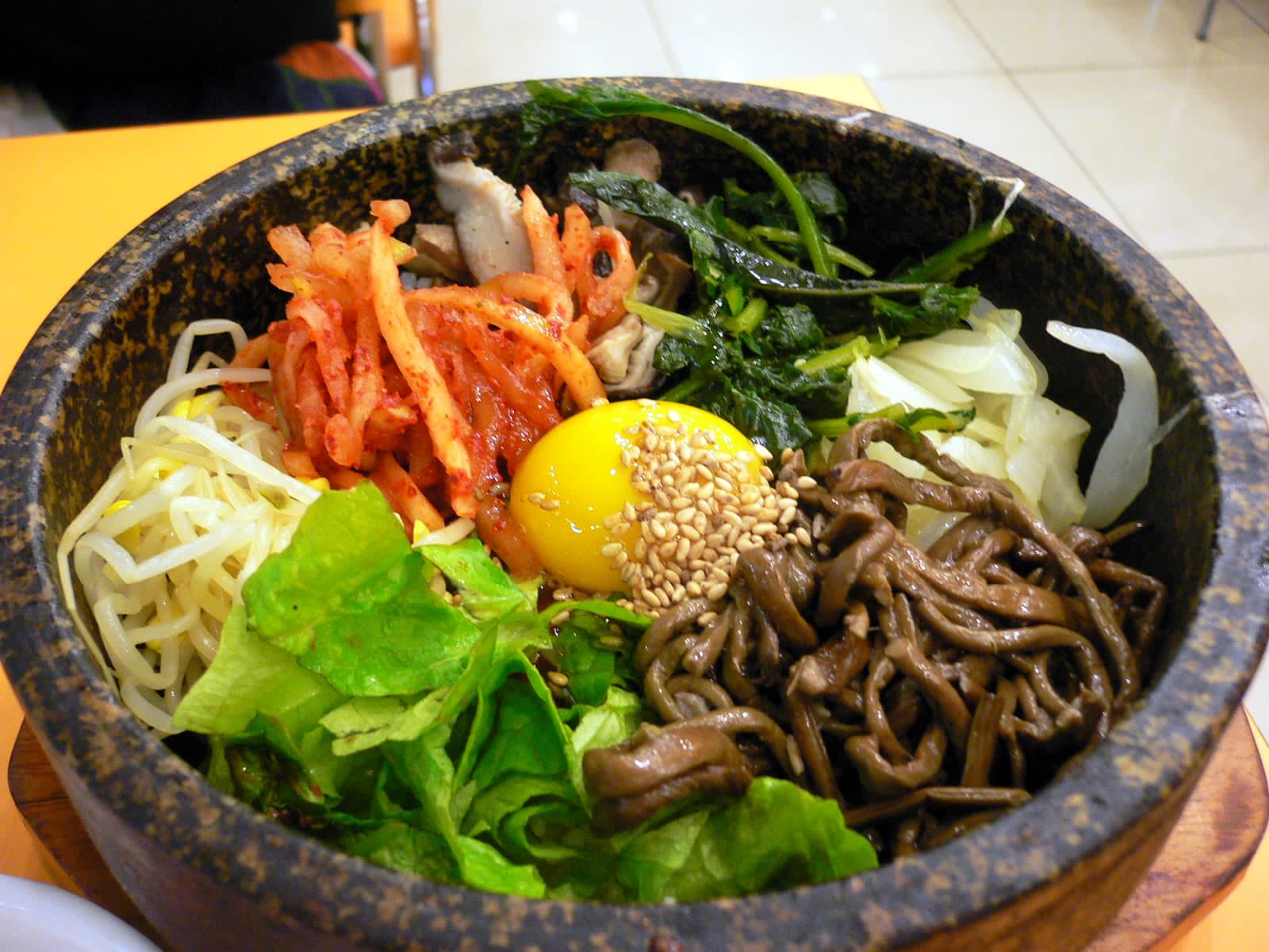 Bibimbap — a korea cuisine main course dish from Korea — featuring bowl-format, stir-before-eating, vegetable-layered